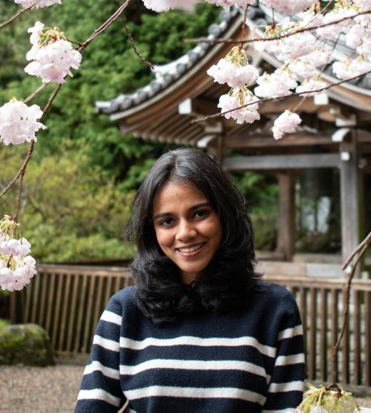 Woman in front of flowering tree wearing striped blue top