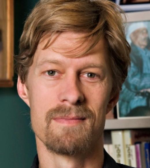 Man with goatee standing in front of bookcase