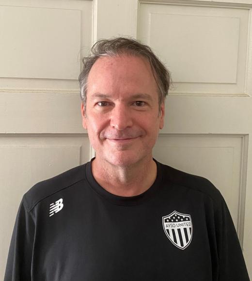 A man wearing a black shirt with a AYSO United shield logo