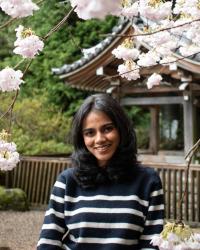 Woman in front of flowering tree wearing striped blue top