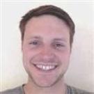 A photo of a man with short brown hair smiling at the camera