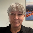 a woman smiling infront of a photo of a bridge