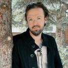 A man standing by a tree wearing a black shirt