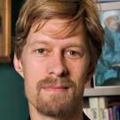 Man with goatee standing in front of bookcase