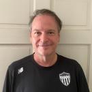 A man wearing a black shirt with a AYSO United shield logo 